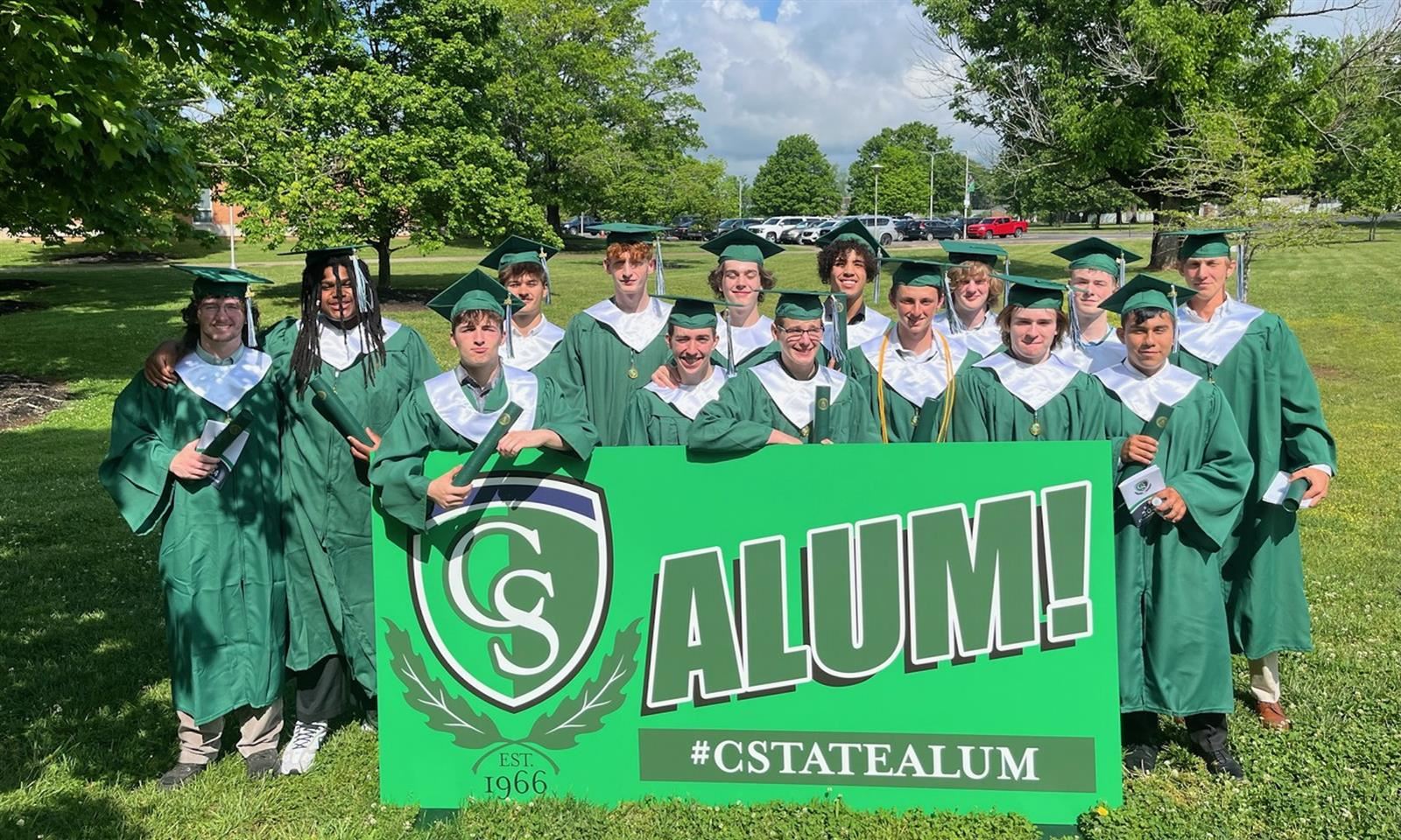 Students dressed in graduation robes smile